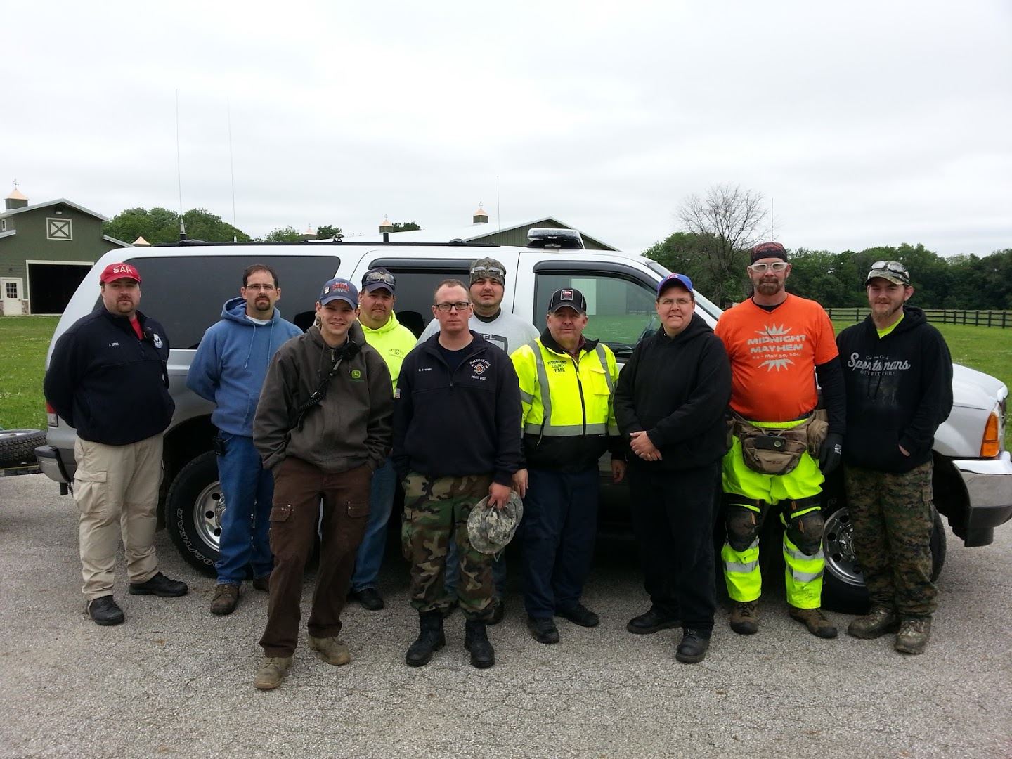 Image of 10 Men of the Search and Rescue Team standing in Front of White SUV